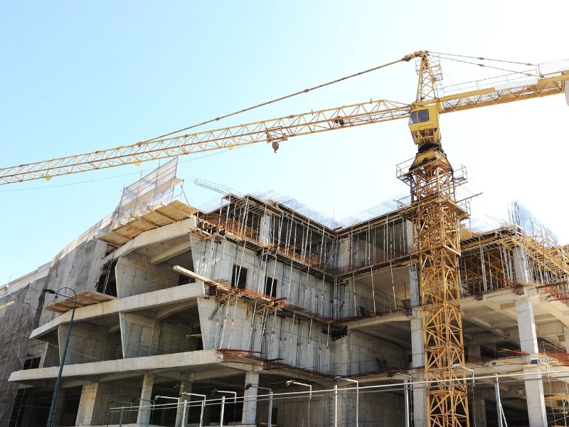 Multi-story commercial building under construction with a tower crane in Grand Rapids, MI, illustrating active construction project management and site coordination.